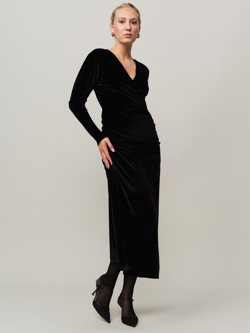 Woman wearing a black dress against a plain background